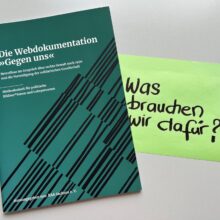 Foto der Broschüre "Die Webdokumentation 'Gegen uns'", daneben liegt ein großes Post-It, darauf die Frage geschrieben: "Was brauchen wir dafür?"